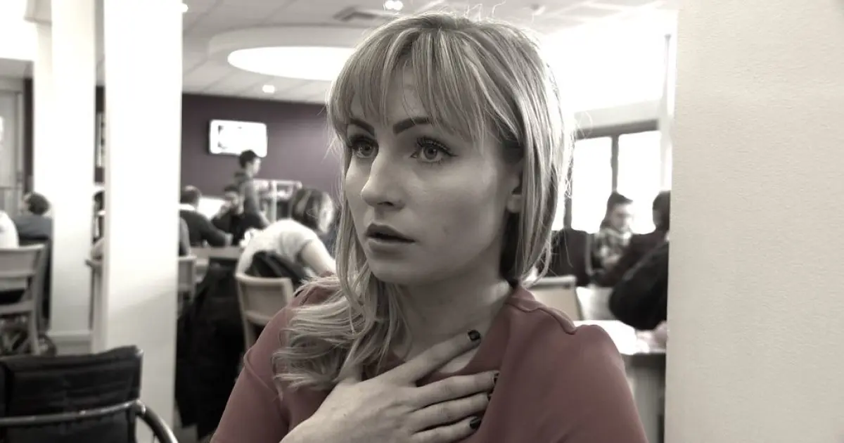 Жінка тримає руку на грудині