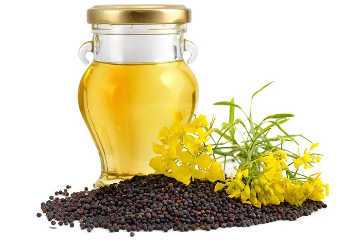 Рапсова олія в скляному глечику, квіти і зерна рапсу
