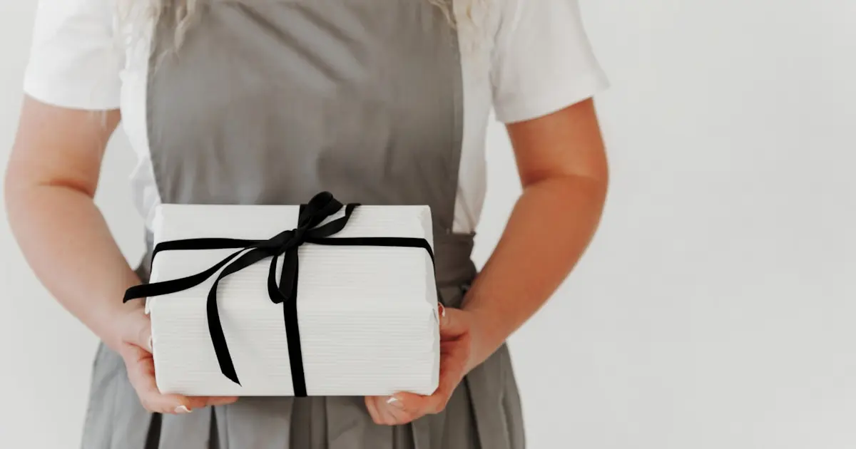 a woman in an apron holding a wrapped present