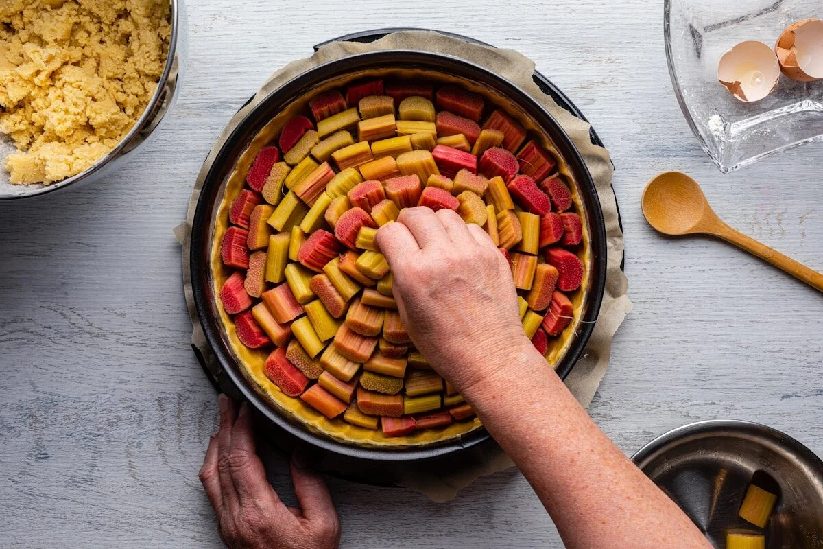 викладає шматочки ревеню на тісто