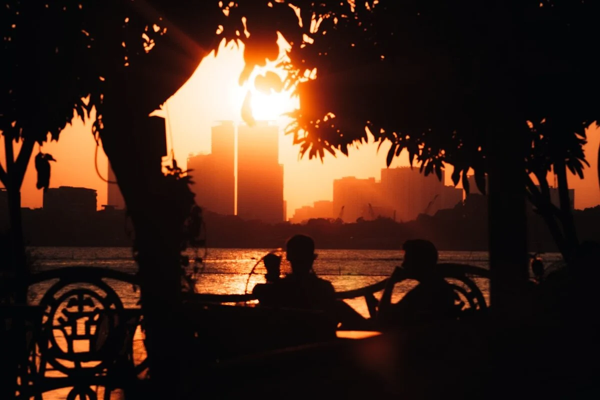 люди на заході сонця стдять на лавці в парку